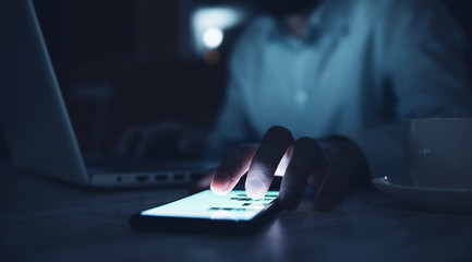 man hand smart phone with computer on dark room