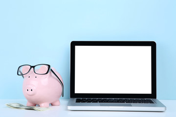 Poster - Laptop computer with piggybank and dollar banknotes on blue background