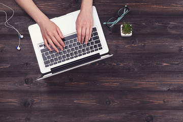Poster - Woman working on laptop computer with glasses and earphones on wooden table
