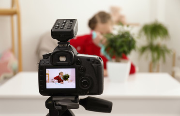 Cute little blogger with plant recording video at home, focus on camera