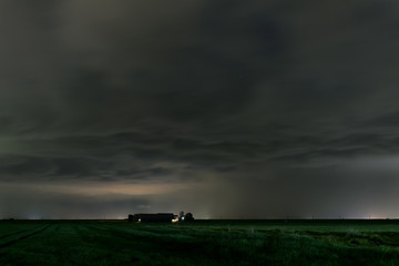 Wall Mural - threatening storm clouds over a farm at night