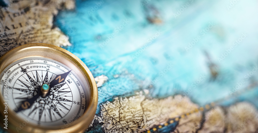 Magnetic compass on world map.Travel, geography, navigation, tourism and exploration concept background. Macro photo. Very shallow focus. - obrazy, fototapety, plakaty 