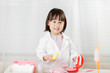 toddler girl pretend play  doctor role  at home against white background