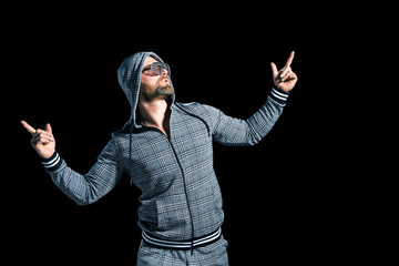 man in a grey suit with a hood in disco glasses against a dark background in the studio. Isolate