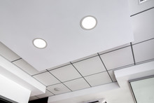 Multi-level Ceiling With Three-dimensional Protrusions And A Suspended Tiled Ceiling With A Built-in Round Led Light, White Color.