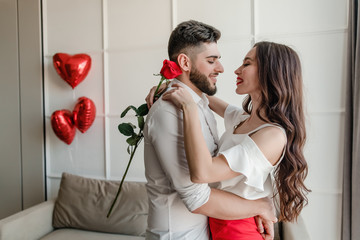 couple man and woman in love with red rose and heart shaped balloons at home