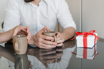 Wall Mural - cups with drink for man and woman at table with gift at home