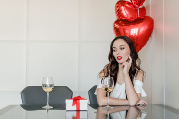 Wall Mural - lonely woman at home with present and heart shaped balloons drinking wine