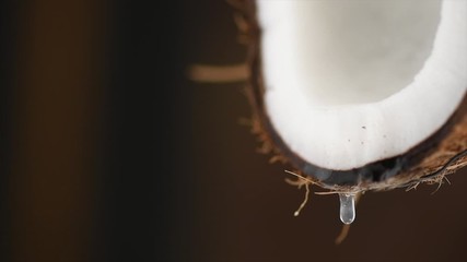 Canvas Print - Coconut pouring water, dripping coconut milk, drops of coco nuts oil over brown background. Tropical Coco nut closeup. Healthy Food, skin care concept. Vegan food. 4K UHD video, slow motion