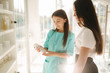 © Aleksandr - Female cosmetologis show to client cosmetology product. Doctor recommends different serum and face masks. Woman in cosmetoligy clinic choose feca balm