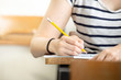 © panitan - high school,university student study.hands holding pencil writing paper answer sheet.sitting lecture chair taking final exam attending in examination classroom.concept scholarship for education abroad