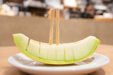 Wall Mural - Juicy melon sliced on plate at restaurant on background.