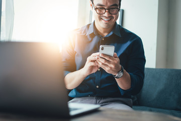 using cell phone.hand holding texting message on screen mobile chatting friend ,search internet information sitting on sofa in office.technology device contact communication connecting people concept