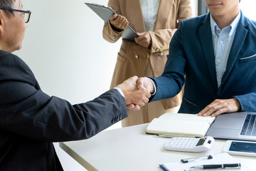 Sticker - businessman shake hand at the office table between computer