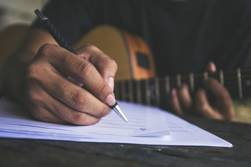 artist songwriter thinking writing notes,lyrics in book at studio.man playing live acoustic guitar relax chill.concept for musician creative.composer work process.people relaxing time with instrument