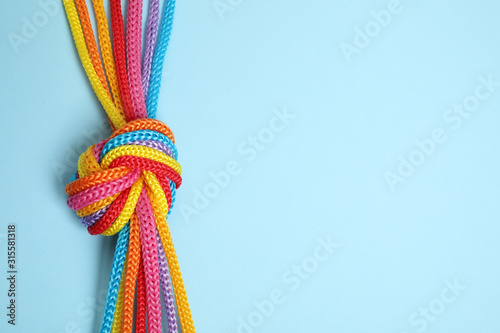 Cuadros en Lienzo Top view of colorful ropes tied together on light blue background, space for text