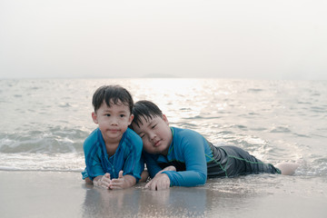 A boy is playing sand and swimming with his brother on the beach.