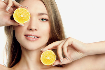 portrait of pretty young woman holding slices of orange, facial care