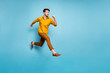 © deagreez - Full length profile photo of funny excited guy jumping high running speed almost get finish line wear yellow shirt pants isolated blue color background