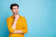 © deagreez - Photo of freelancer guy seriously looking side empty space holding arm on chin thinking over startup creative idea wear yellow shirt isolated blue color background