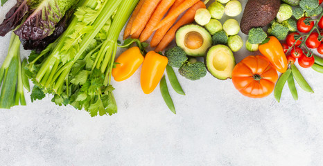 Fresh raw ingredients tomatoes cucumbers lettuce pepper avocado parsley onion broccoli peas on the white table, top view, copy space, banner, selective focus