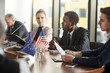 © AnnaStills - African young businessman sitting at the table together with his partners and speaking during business conference at office