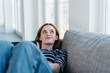 Leinwandbild Motiv Young woman reclining on a couch daydreaming