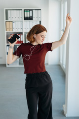 Wall Mural - Young woman dancing to music in the office