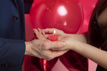Wall Mural - valentine's day celebration, close up of caucasian couple's hands holding heart shaped candle on cor