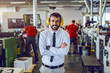 © Dusan Petkovic - Attractive Caucasian bearded director in shirt and tie and with antiphons on ears standing with arms crossed in printing shop.