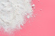 © OlekStock - Scattered heap of washing powder for cleaning clothes lies on pink countertop in laundry. Space for text. Top view