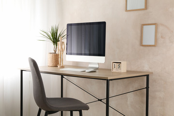 Computer, plant and wood man on wooden table. Workplace room