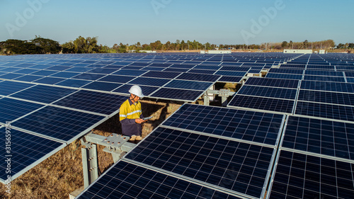 Technician and investor walking in Solar cell Farm through field of solar panels checking the panels at solar energy installation.Solar cells will be an important renewable energy of the future.