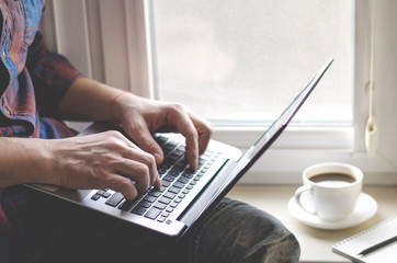 Man using laptop in home office. Male hands typing on keyboard