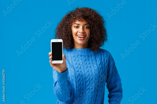 Look At My Score Happy And Proud Good Looking African American Woman Browsing Dating App Showing Smartphone Screen Camera Take A Look Standing Blue Background In Winter Sweater Buy This Stock Photo And