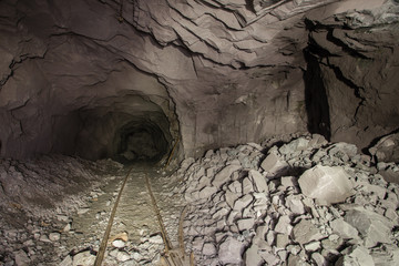 Underground gold mine shaft tunnel drift with rails face wall