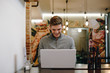 © Westend61 - Young man sitting in a restaurant typing on his laptop while smiling