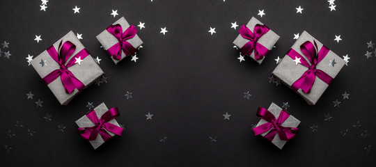 New years background. Christmas gifts with red ribbon on black b