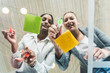 © Westend61 - Two young businesswomen working on adhesive notes on glass table