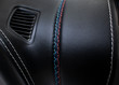 Multicolored seam on a black leather car panel