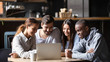 © fizkes - Diverse friends hang out in cafe using laptop