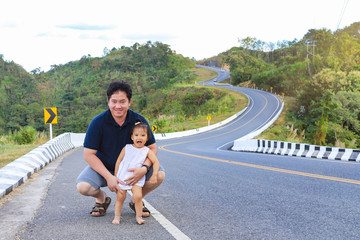 Father and his daughter on roadside with beautiful wavy road  in background