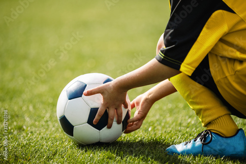 Child playing with soccer ball on grass venue. Little kid holding in both han...