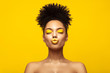 Enjoyed African American Fashion Model portrait . Satisfied Brunette young woman with afro hair style and closed eyes show kiss,creative yellow make up, lips and eyeshadows on colorful background.