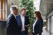 © Westend61 - Smiling business people talking in modern office building