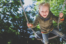Portrait Of Happy Little Boy On A Swing