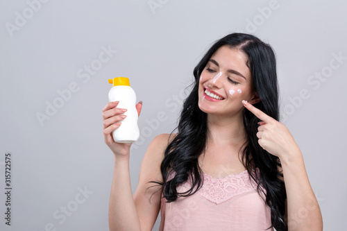 Cuadros en Lienzo Young woman with sunscreen on a gray background