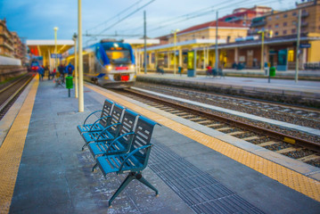 Picture of bench on the train station with blurred train on the background