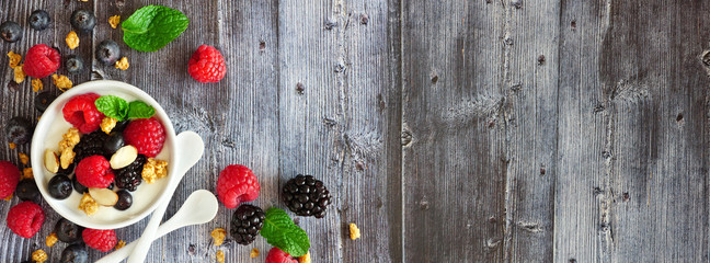Wall Mural - Healthy yogurt with fresh berries and granola. Banner with corner border against a rustic wood background. Copy space.