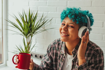 Wall Mural - girl with headphones and coffee cup listening to music at home